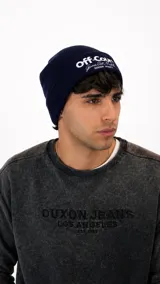 Gorro de lana tejido en color azul marino con diseño de doblez y bordado frontal con texto en blanco.