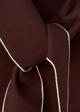 Top marrón sin mangas, de corte recto y ajuste cómodo, con cuello alto y una bufanda o lazo integrado con bordes claros.