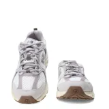 Championes New Balance modelo 530, con diseño retro-deportivo. Presentan una capellada de malla blanca transpirable con refuerzos sintéticos en tonos gris claro y lila. Incorporan entresuela con tecnología ABZORB para amortiguación y suela de goma en color marrón.