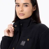 Chaqueta de polar tipo sherpa color negro, con cierre frontal de botones a presión metálicos y cuello alto. Presenta un bolsillo en el pecho con solapa de nylon y bolsillos laterales, con puños y cuello elásticos.