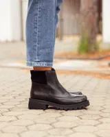 Botinetas de cuero negro con suela track dentada. Presentan una combinación de texturas en el lateral, con una sección de cuero liso y otra con textura grabada, además de un panel elástico en la parte superior del tobillo.