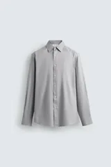 Camisa de corte slim fit confeccionada en tejido de algodón con textura. Presenta cuello italiano, manga larga con puños abotonados y cierre frontal de botones.