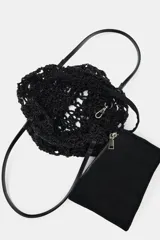 Bolso tipo shopper pequeño de crochet negro, con asas de hombro de material liso negro y una bolsa interior con cierre de cremallera.