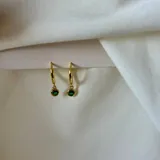 Aros dorados tipo argolla con dije colgante de cristal verde.