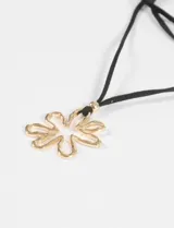 Collar largo de cordón negro con dije metálico plateado en forma de contorno de flor.