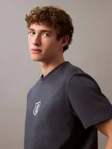 Remera gris oscuro de algodón regenerativo, con cuello redondo, manga corta y logo CK Shield bordado en el pecho.