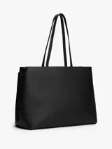 Cartera tipo tote de Tommy Hilfiger en color negro, confeccionada en poliuretano con textura granulada. Presenta doble asa superior, cierre principal y un diseño central decorativo con tachas metálicas y el logo monograma TH en metal dorado.
