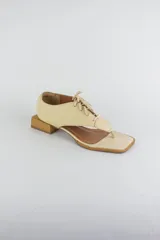 Sandalias de cuero color beige con diseño de ojota acordonada en el empeine, puntera cuadrada y taco bajo cuadrado.