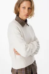 Sweater de silueta holgada en color crudo, con cuello redondo, mangas largas y puños anchos acanalados.