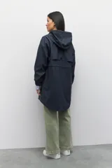 Piloto verde militar de manga larga con capucha y forro de color amarillo. Cuenta con dos bolsillos laterales con solapa, cordones ajustables, elástico en los puños, cierre y botones metálicos.