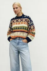 Sweater de lana merino con estampado Fair Isle en tonos azul marino, beige, naranja, verde oliva y bordó. Tiene cuello redondo y mangas largas.