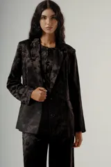 Blazer de corte sastrero y silueta relajada, color negro con estampado floral tono sobre tono. Presenta solapas clásicas, cierre frontal con dos botones y bolsillos laterales con solapa.