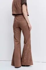 Pantalon de gamuza sintética color marrón, de corte recto y tiro alto, con detalles bordados en la parte frontal.