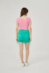 Minifalda verde con frunces laterales ajustables con cordones.