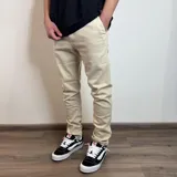 Jean de corte skinny color beige, con diseño de cinco bolsillos y cierre frontal con botón y cremallera.