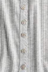Top de manga corta de punto pointelle suave, color gris, con ajuste entallado, escote en U y hilera de botones frontales. Presenta ribete levemente festoneado en el escote y la tapeta.