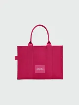 Bolso tote color fucsia, modelo The Doggy Bag, con texto estampado en blanco que dice "THE DOGGY BAG MARC JACOBS". Presenta un diseño acolchado vertical y asas de mano.