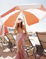 Falda playera larga estilo pareo, confeccionada en gasa estampada con diseño de algas marinas en tonos rosa, celeste, verde y blanco. Presenta cinturón anudado en la cintura y volantes en la abertura y el bajo.