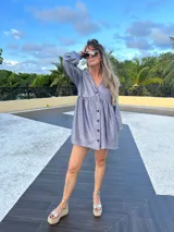 Vestido corto dorado con textura brillante, corte holgado, mangas largas con volados y cuello redondo.