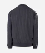 Campera deportiva de helanca color gris oscuro, con diseño de raya diplomática fina, cuello bomber, cierre frontal y bordados en el pecho.