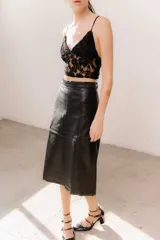 Pollera midi de eco cuero color beige, de corte recto y tiro alto, con costuras verticales decorativas y detalle de cinturón fino con flecos.