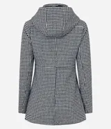 Saco largo con capucha y estampado pied de poule en blanco y negro. Tiene cuello alto, cierre con botones y cremallera, bolsillos y mangas largas.