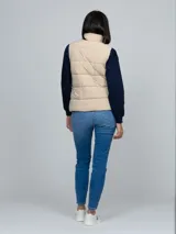 Chaleco acolchado de cuello alto con cierre frontal de cremallera y dos bolsillos laterales de ojal. Presenta un diseño moderno y ligero, con detalles distintivos de la marca.