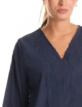 Blusa de algodón azul marino con bordado floral al tono. Presenta escote en V con terminación festoneada y mangas largas ligeramente abullonadas con puños abotonados. Su diseño es de silueta fluida y relajada.