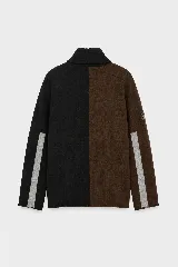 Polera de tejido lambswool con diseño bicolor en tonos neutros. Presenta cuello alto tejido, mangas largas con franjas laterales en color marrón y detalle de bordado artesanal con tres pequeñas líneas horizontales en colores vibrantes.