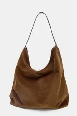 Bolso tipo shopper de textura acanalada efecto pana, color marrón. Cuenta con asa de hombro, cierre frontal con tira y hebilla metálica, y bolsillo interior con cremallera.