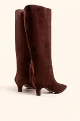 Bota de caña alta confeccionada en gamuza color marrón, con diseño minimalista, punta fina y taco kitten heel de 6 cm.