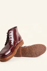 Bota acordonada de cuero vacuno con acabado charol color suela, con suela de goma tipo crepe y costuras reforzadas.