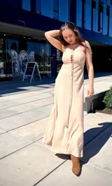 Vestido largo color beige, con breteles finos, escote con cordones cruzados y falda acampanada.