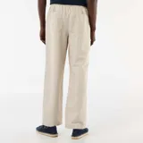 Pantalón de lino color beige con sutiles rayas verticales oscuras, de corte recto y holgado, con cintura elastizada y cordón ajustable.