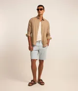 Bermuda masculina slim confeccionada en sarga de algodón con elastano, con bolsillos laterales, bolsillos traseros con botón, trabillas en la cintura y cierre frontal de botón y cremallera.