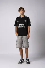 Remera tipo chomba de tejido de punto color blanco, con cuello polo y diseño de rayas verticales sutiles. Presenta estampado gráfico frontal con texto y logo, además de detalles de rayas negras en los hombros.