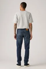 Pantalón de jean azul oscuro, corte slim fit, con pierna cónica y tiro medio. Diseño clásico de cinco bolsillos.