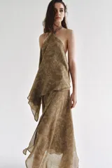 Top de cuello halter con tiras cruzadas para atar al cuello, hombros descubiertos y bajo asimétrico con caída drapeada y textura rústica con estampado sutil.