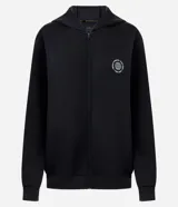 Campera deportiva Get Over confeccionada en mezcla de poliéster, viscosa y elastano, de color negro con capucha fija, cierre frontal y bolsillos laterales. Cuenta con un pequeño estampado circular con lettering en el pecho.