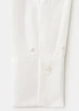 Camisa oversize blanca de mezcla de algodón y lyocell, con cuello camisero, manga larga, puños abotonados y detalle de perlas aplicadas en toda la prenda.