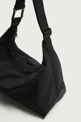 Bolso de hombro negro de tejido técnico, con compartimento principal con cierre de cremallera, bolsillo interior con cremallera y asa de hombro ajustable con detalle de mosquetón.
