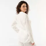 Camisa larga blanca de lino, con cierre frontal de botones, mangas largas y lazo ajustable en la cintura.
