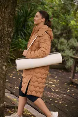 Campera larga color marrón con diseño acolchado, capucha desmontable, cierre frontal con botones a presión, bolsillos laterales con cierre, puños elásticos y cintura ajustable.