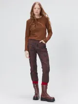 Remera de manga larga con cuello a la base, confeccionada en tejido de punto acanalado color beige. Presenta un logo bordado en el centro del pecho.