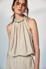 Top de cuello halter con diseño holgado y fruncido. Presenta detalle de abalorios decorativos en el escote y bajo con acabado elástico.