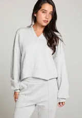 Buzo gris jaspeado de polar, con cuello en V y mangas largas.