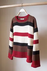 Sweater de tejido de punto a rayas horizontales en color marrón, rojo, blanco y negro, con cuello redondo y mangas largas.