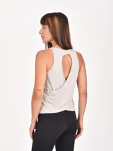 Musculosa deportiva de color gris, con cuello redondo y diseño de espalda cruzada con abertura.