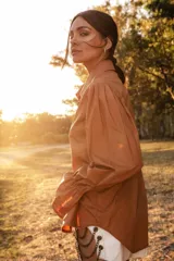 Camisa color camel con botones de madera, cuello camisero, mangas abuchonadas con puños elásticos y silueta relajada.