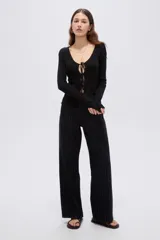 Top de manga larga en tejido de punto con lurex, color negro, de corte ajustado al cuerpo, con escote en V pronunciado y cierre delantero mediante finos lazos para anudar.
